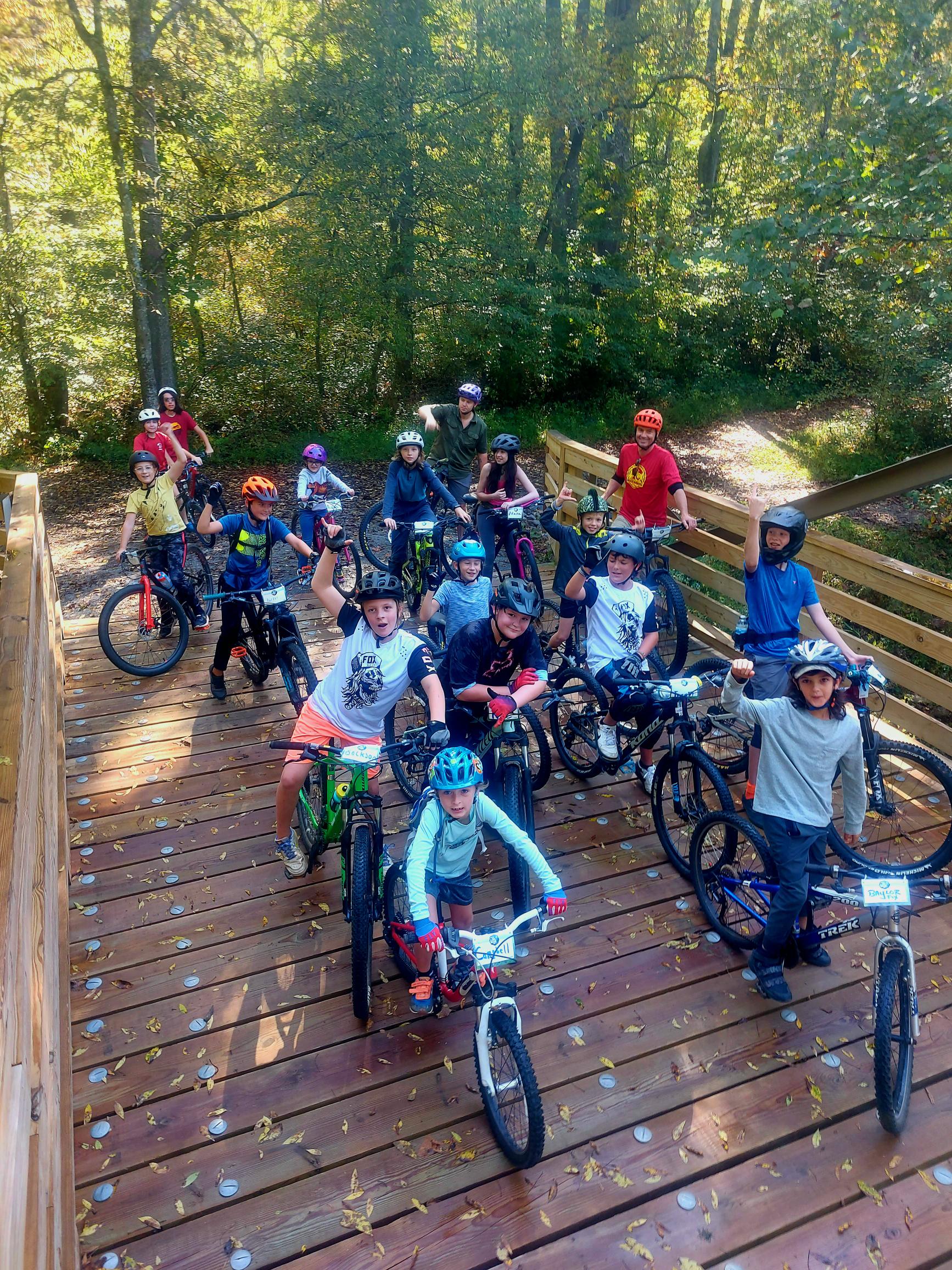 Mountain Bike Group photo on a bridge sitting on their bikes with a few having their fists raised