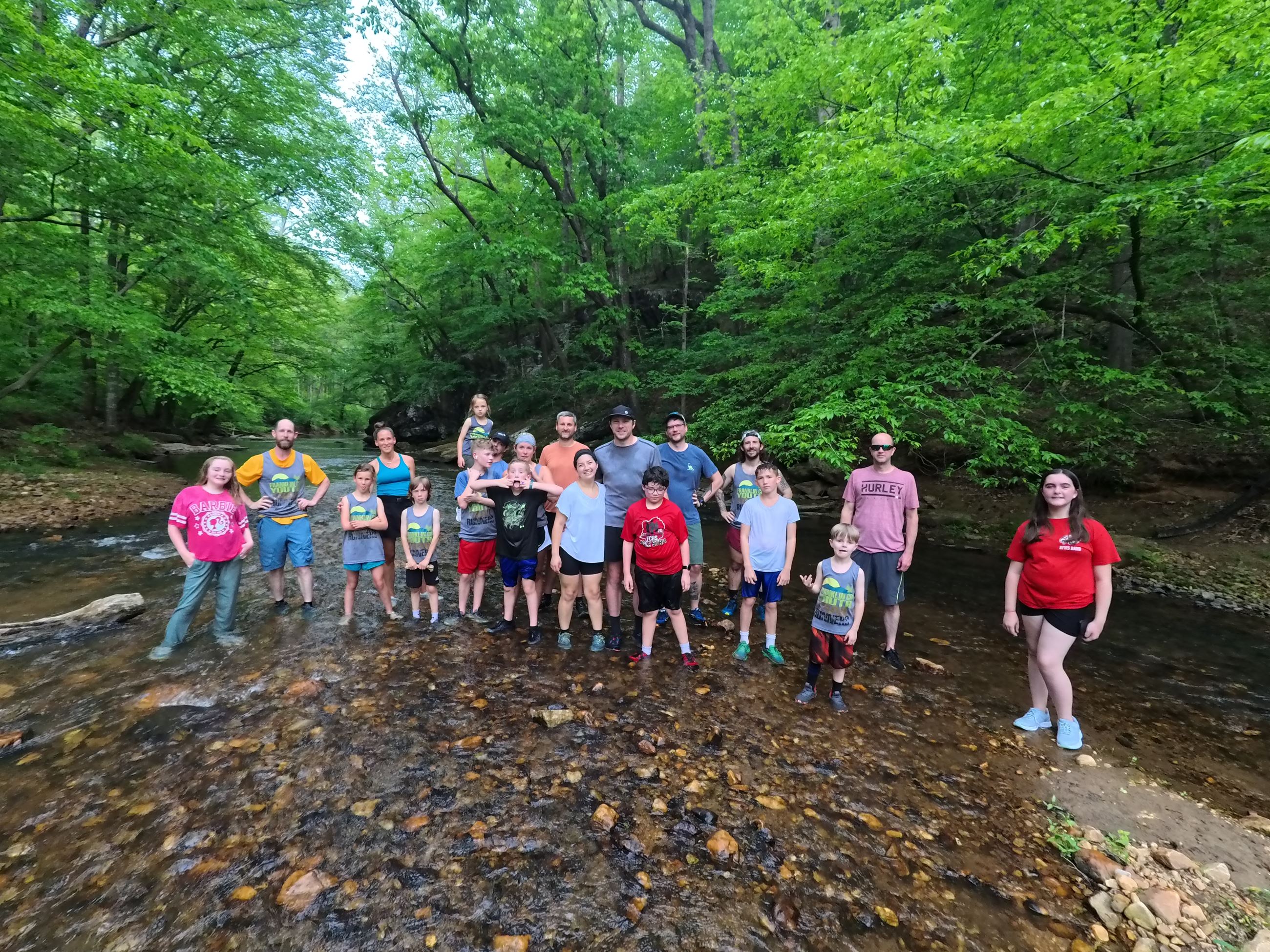 A group of people standing in the shallow spot of the creek